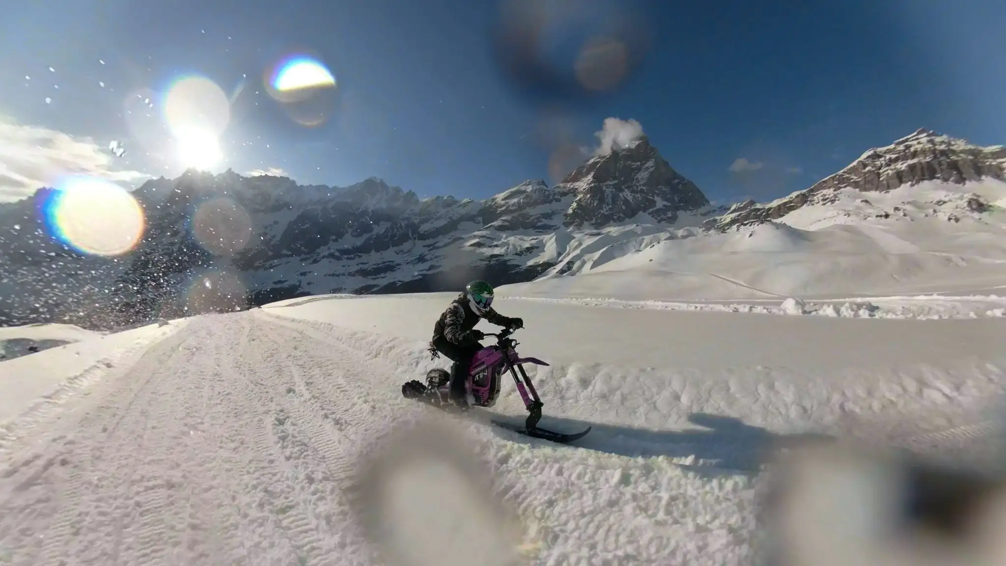 Rider su snowbike in pista con panorama alpino